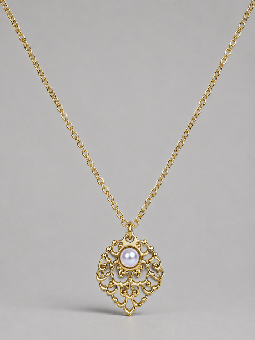 A gold filigree pendant necklace featuring a central white pearl, displayed against a neutral gray background.