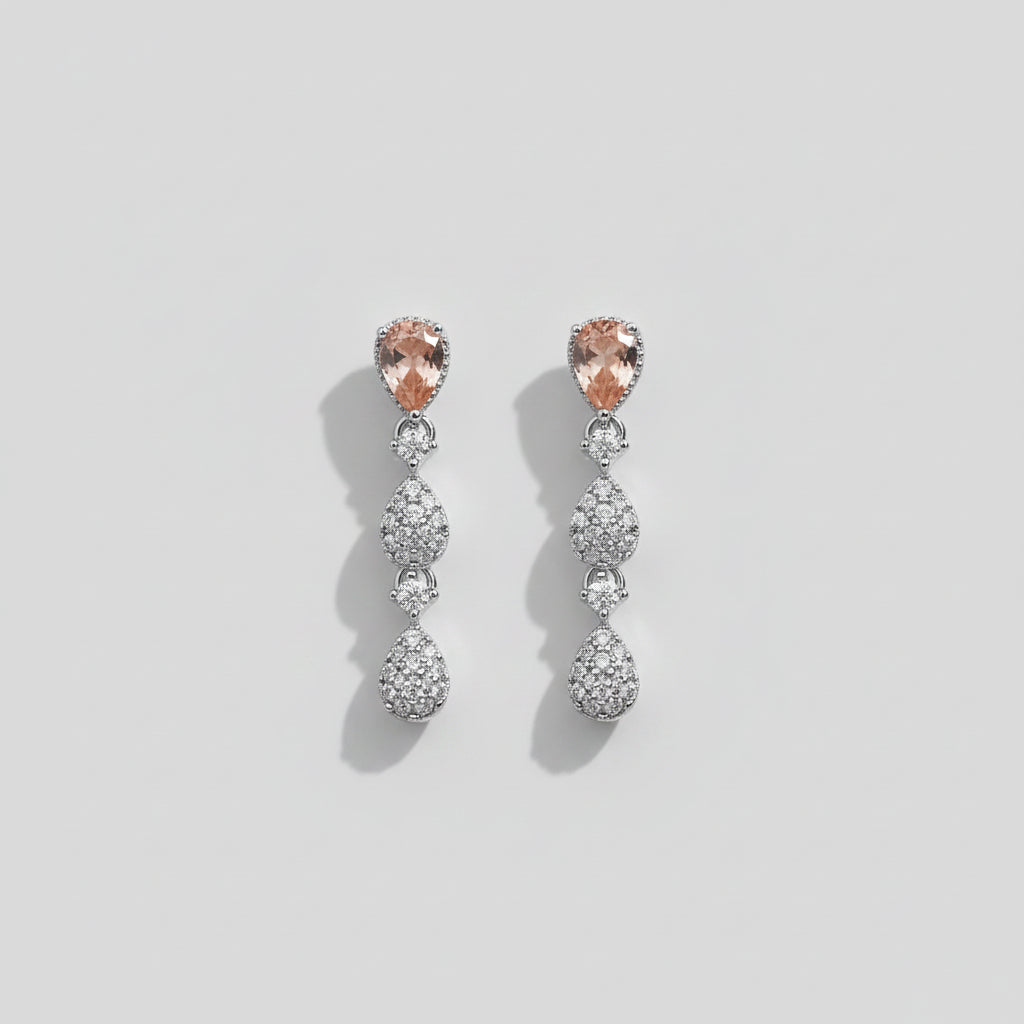 A pair of silver-toned drop earrings with peach-colored marquise-cut center stones and clear teardrop-shaped pavé stones.
