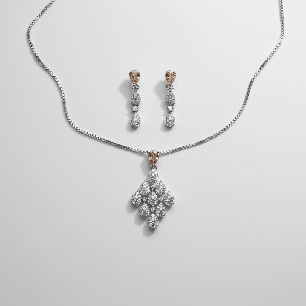 A jewelry set featuring a silver-tone chain necklace with a floral pendant and matching drop earrings.